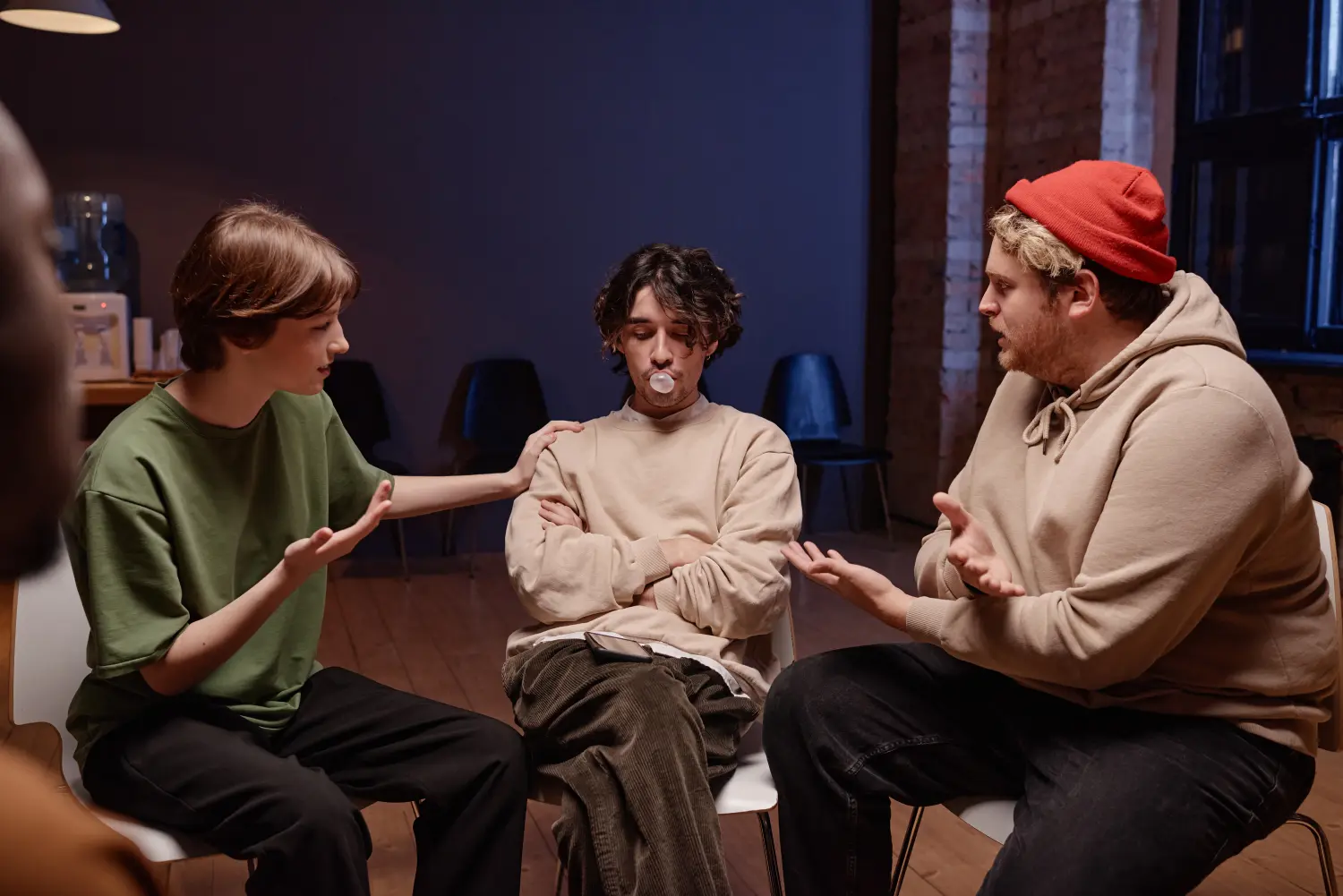 Horizontale Aufnahme von jungen kaukasischen Männern und Frauen, die eine Situation während einer Gruppentherapie nachstellen